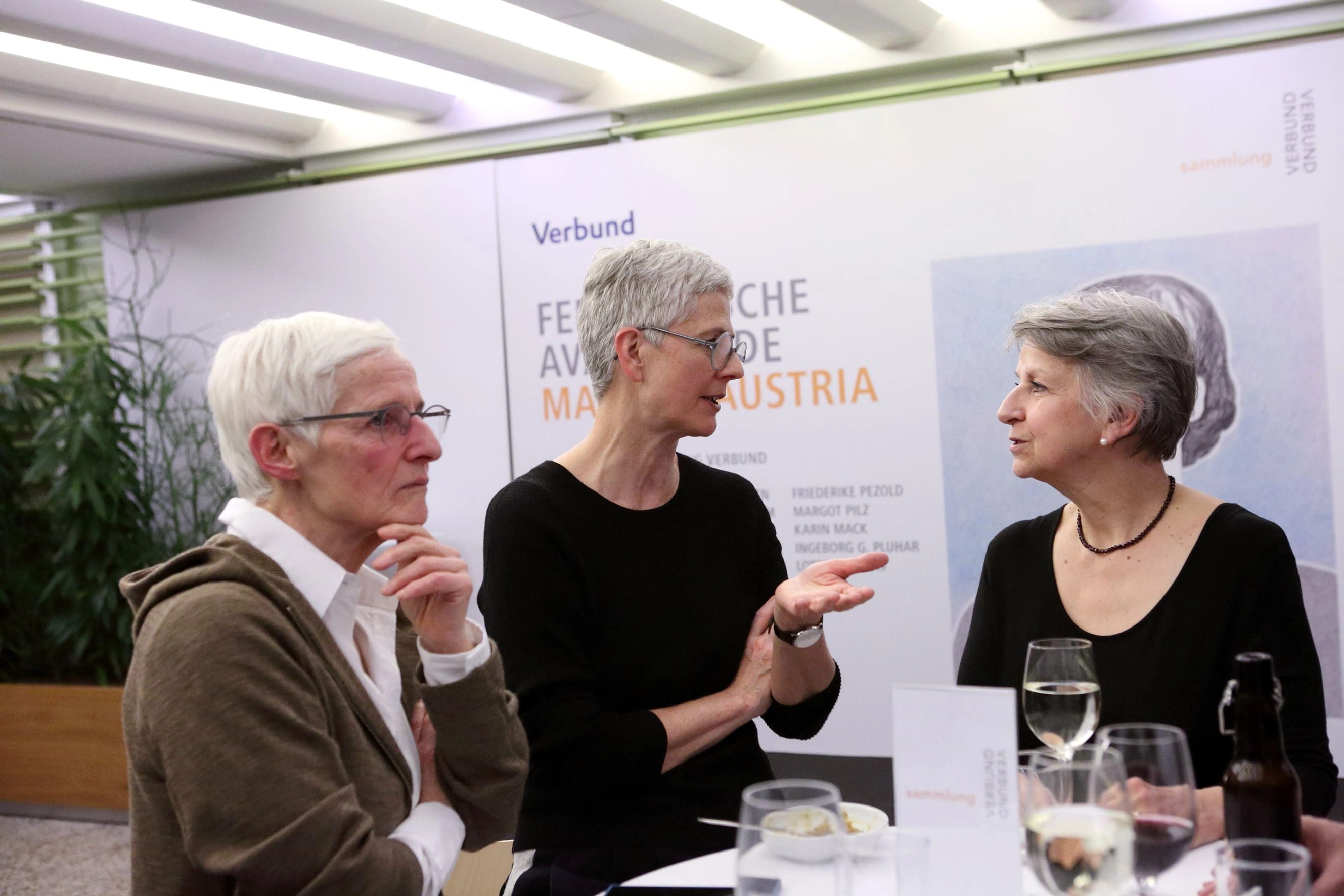 Three visitors to the press conference are engaged in a lively discussion.