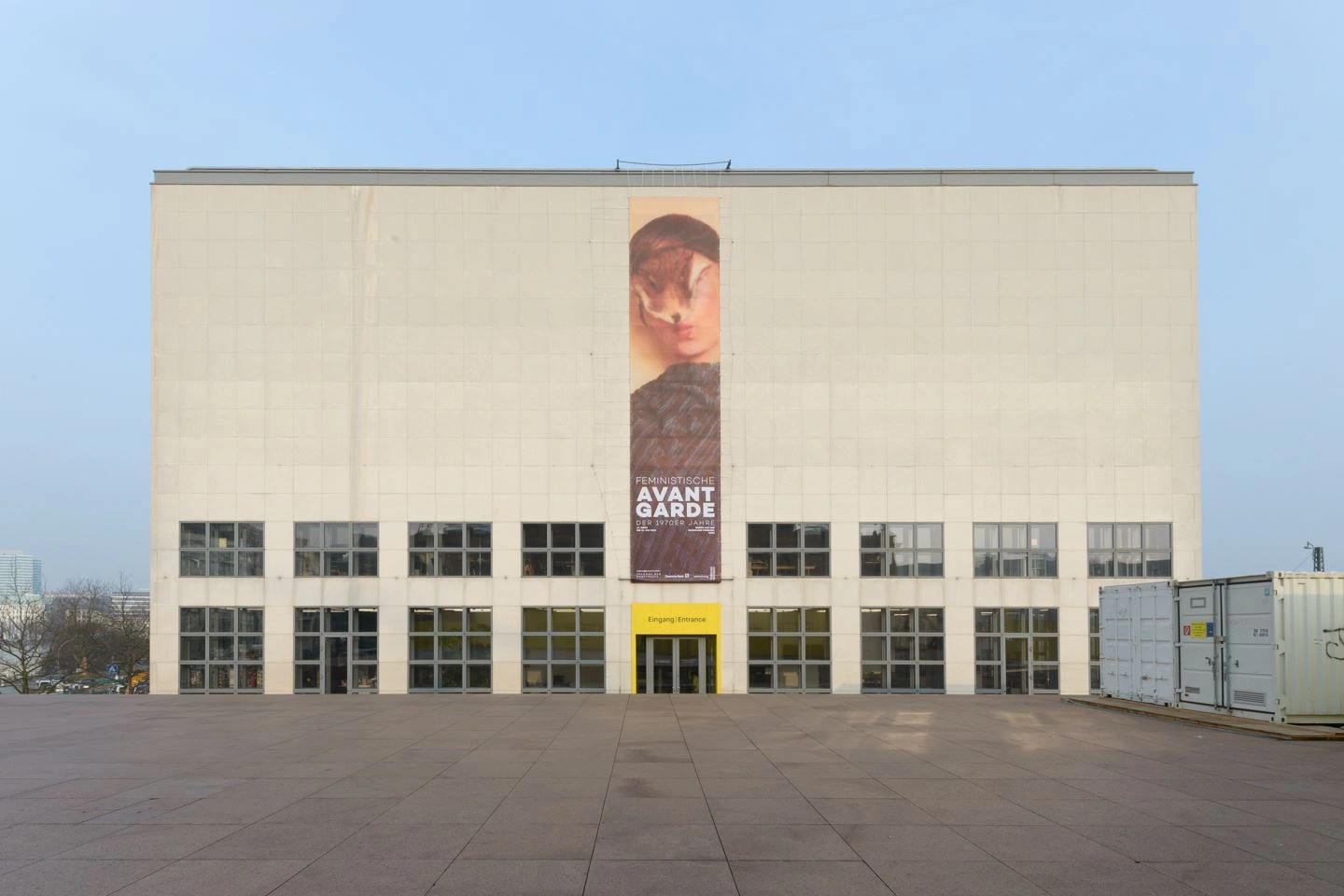 Die Kunsthalle Hamburg von außen an einem sonnigen Herbsttag. In der Mitte hängt das Ausstellungsplakat mit der Aufschrift feministische Avantgarde.