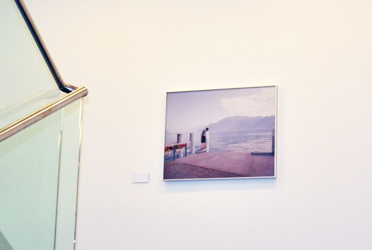 A corner of a bright room featuring an art installation, with a painting of a beachscape hanging on the wall.