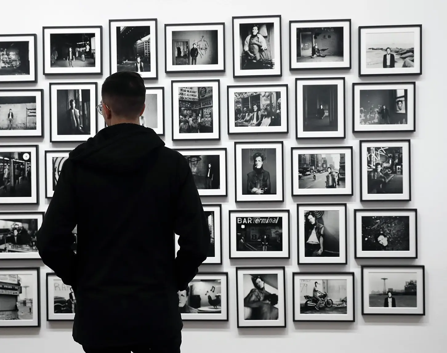 A photo installation by artist David Wojanorwicz hangs on a white wall, showing various aspects of his life.