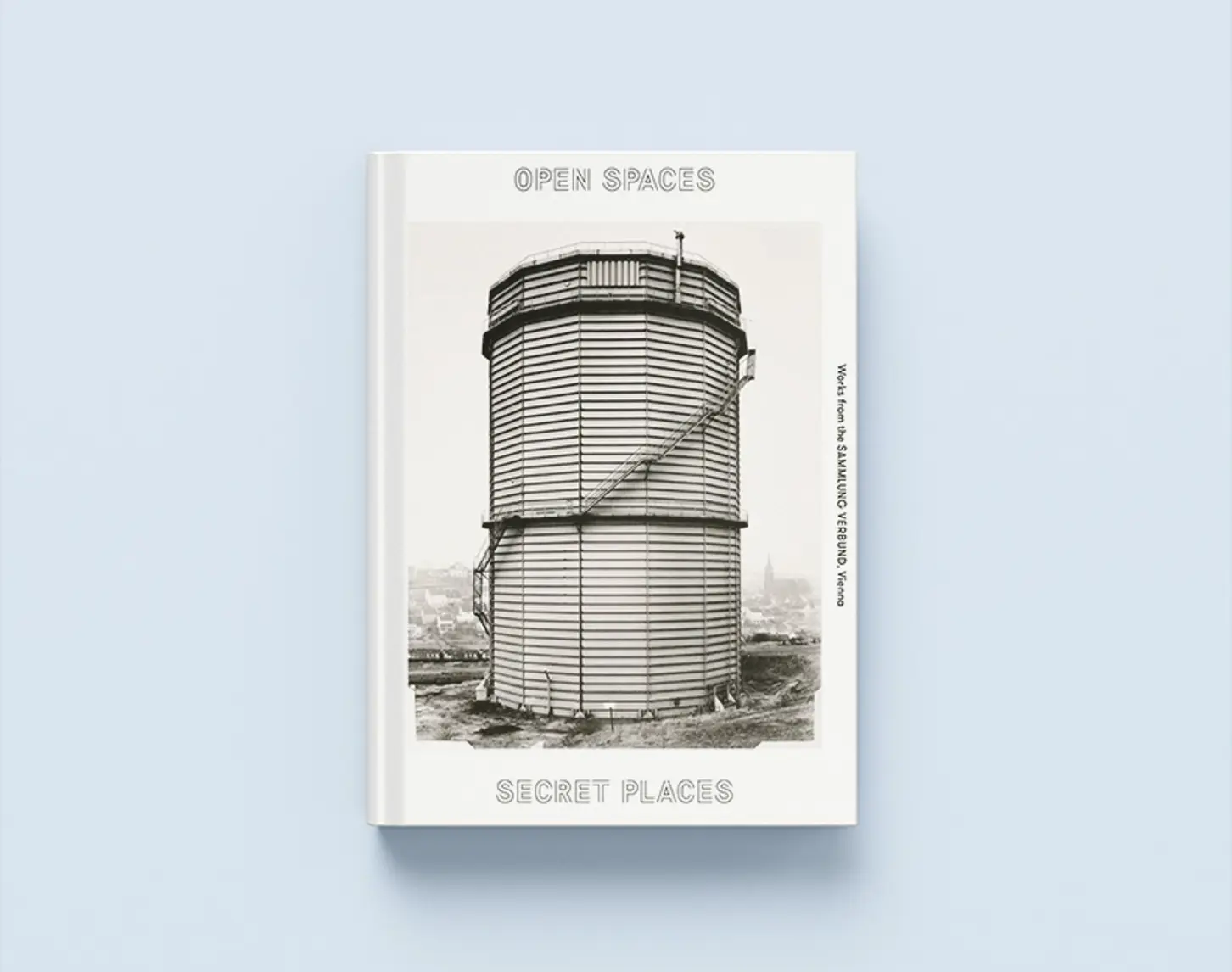 The work catalog for the open spaces / secret places exhibition from 2016 shows the exhibition name in a futuristic typography. In the center of the cover is a black and white depiction of a tall, windowless tower.