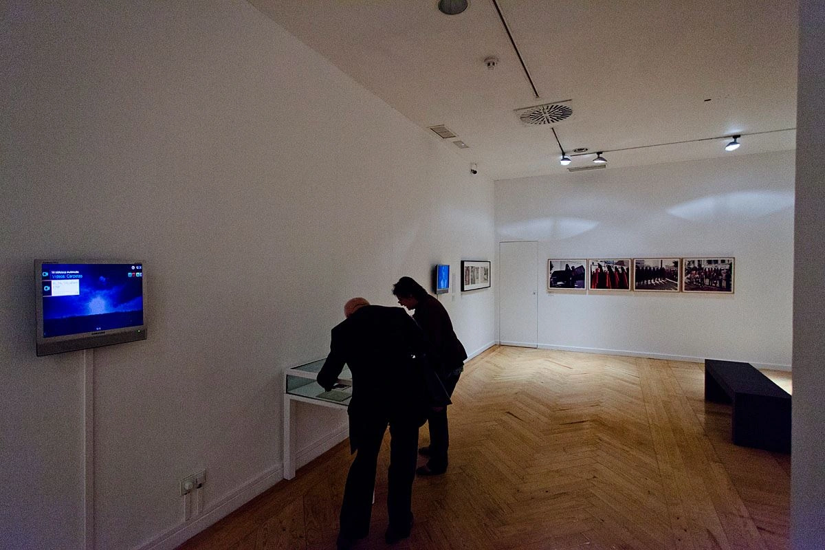 In einem dunklen Ausstellungsraum sind zwei Personen über einen Ausstellungskasten aus Glas gebeugt.