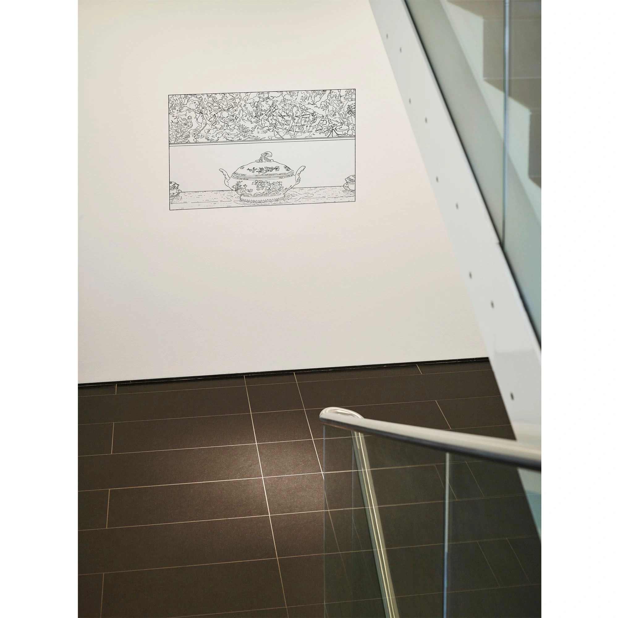 A staircase can be seen facing downwards. On a white wall is a large, landscape-format drawing on which a bowl with a lid stands.