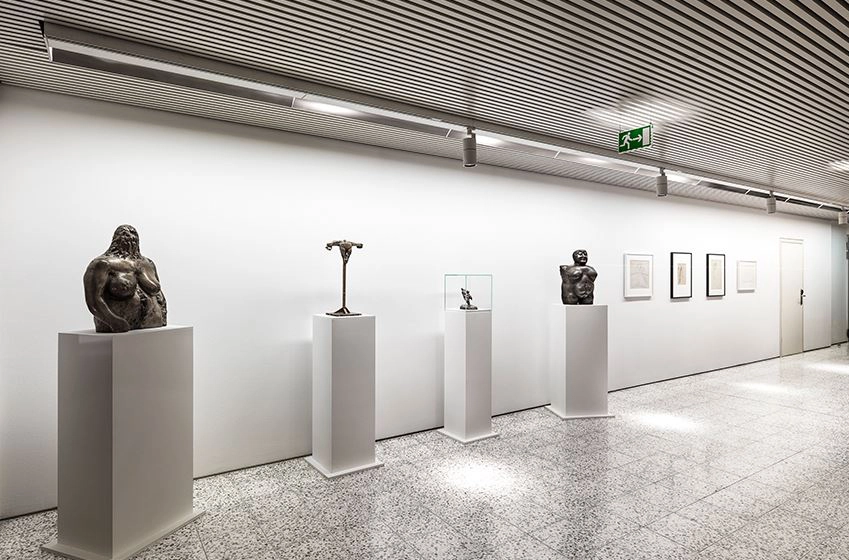 The left-hand side presents four dark sculptures. The right-hand side of the picture shows four images that have been pushed into the background.