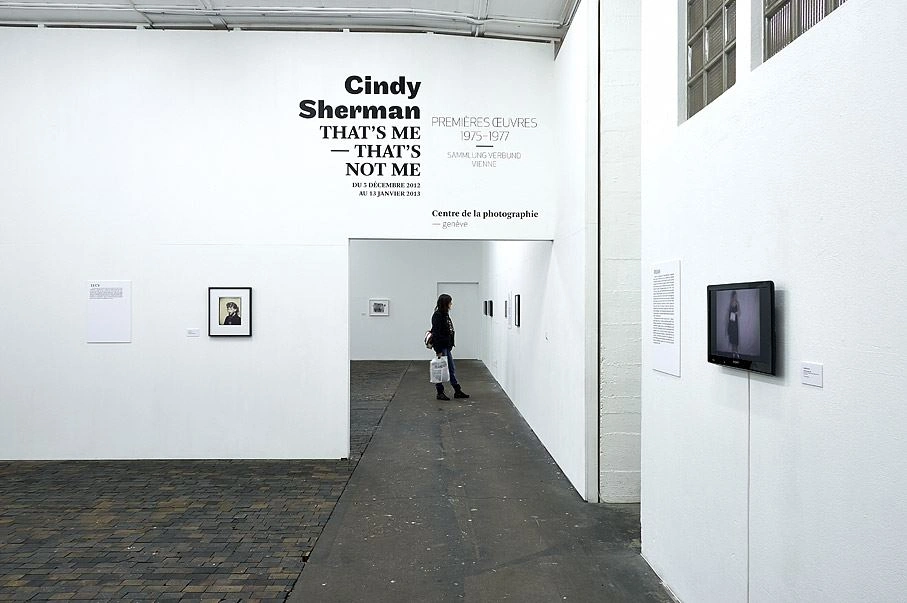 Visitor viewing the Cindy Sherman photo exhibition "That's me – That's not me"  with artworks on white walls.