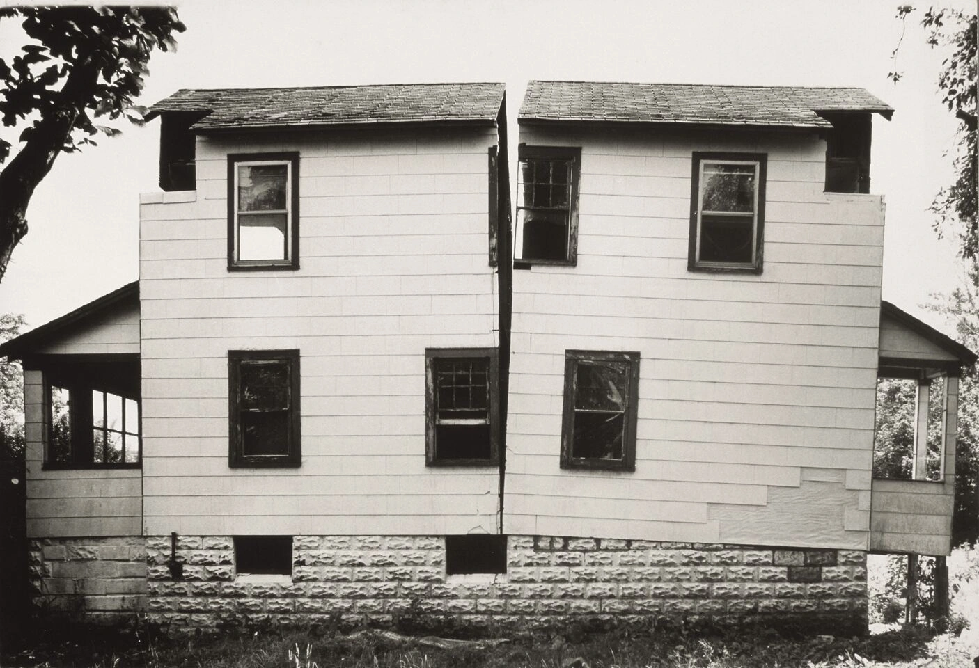 Die Schwarz-Weiß-Fotografie von Gordon Matta-Clark zeigt eine schlichtes Einfamilienhaus, das in der Mitte durchgeschnitten wurde.